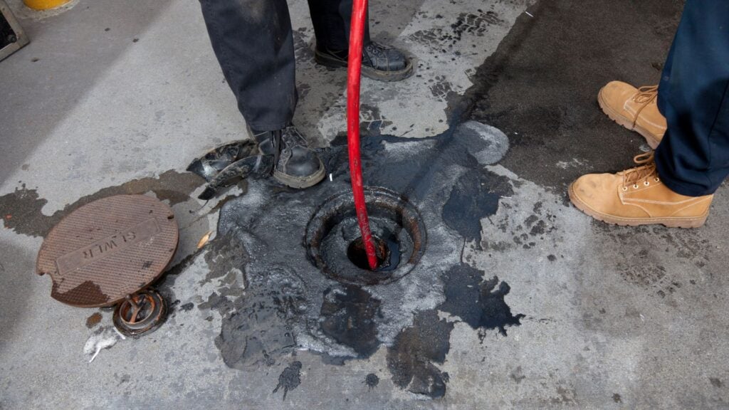 plumber using drain snake to clear clog